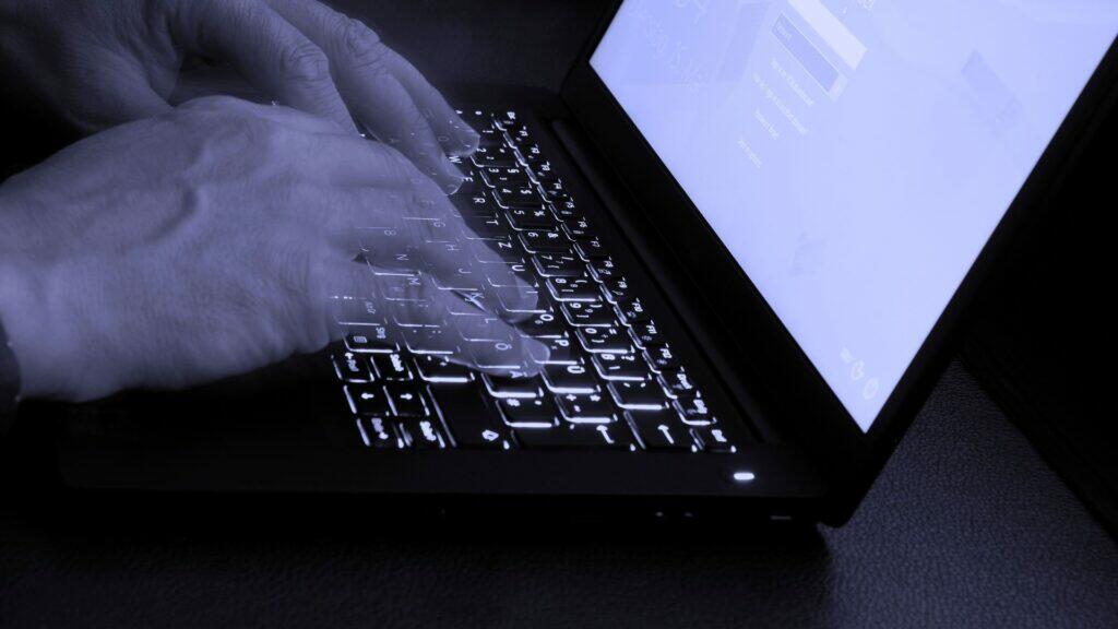 Eine Person tippt im Dunkeln auf einem Laptop. Symbolbild Darknet.